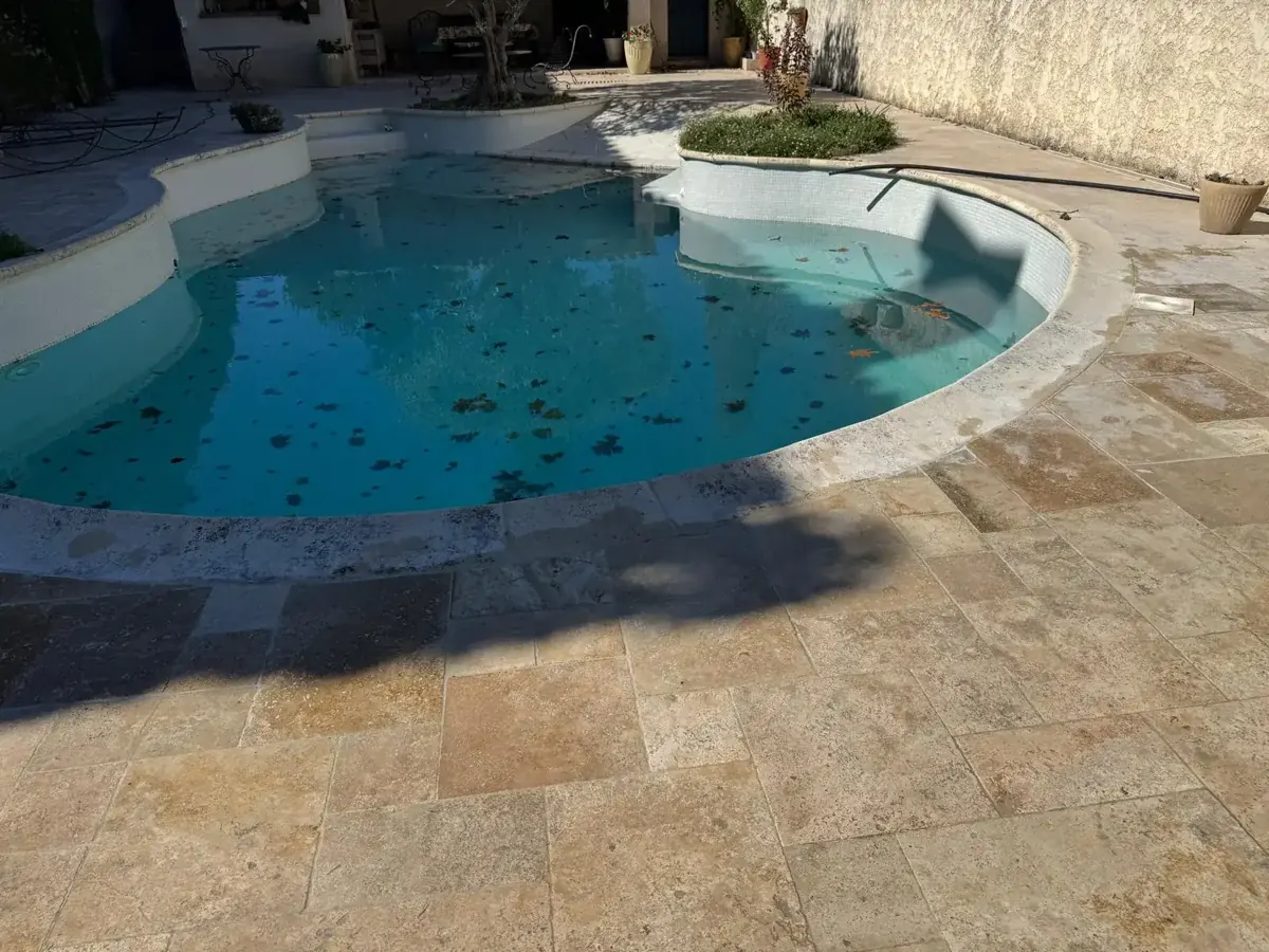 Dalles de travertin format Opus reposées autour de la piscine à Cadenet